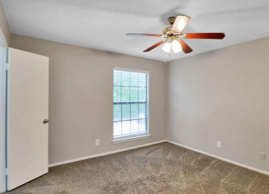 A room with a ceiling fan and a window.