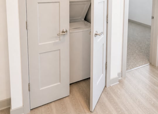A white door is open to reveal a small kitchen.