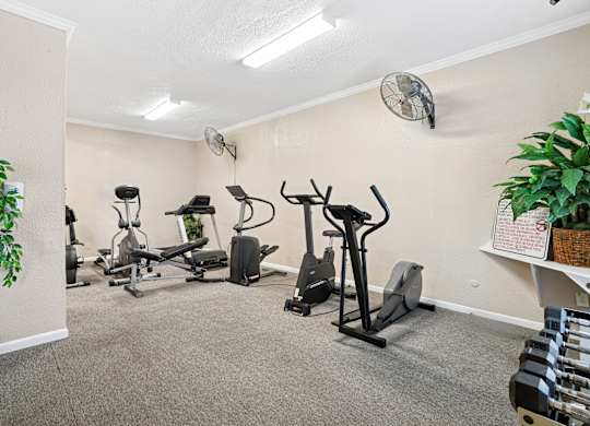 A room with exercise equipment and a fan on the wall.