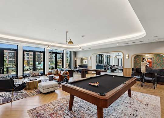 A pool table is in the middle of a room with a view of the city.