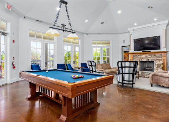A pool table is in the middle of a room with a fireplace and a television.