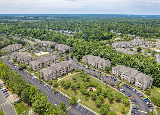 A bird's eye view of a residential area with multiple apartment buildings and a parking lot.