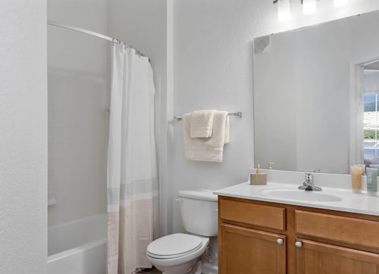 A white bathroom with a toilet, sink, and shower.