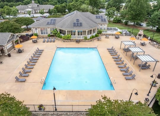 A large swimming pool surrounded by sun loungers and umbrellas.