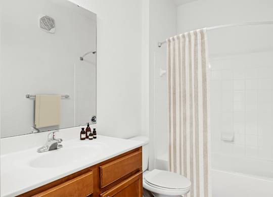 A white bathroom with a toilet, sink, and shower.