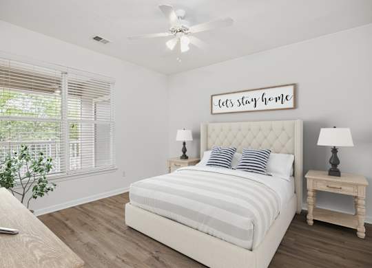 A bedroom with a bed, a ceiling fan, and a window with blinds.
