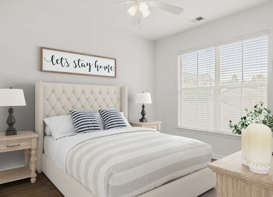 A bedroom with a bed, nightstands, and a ceiling fan.