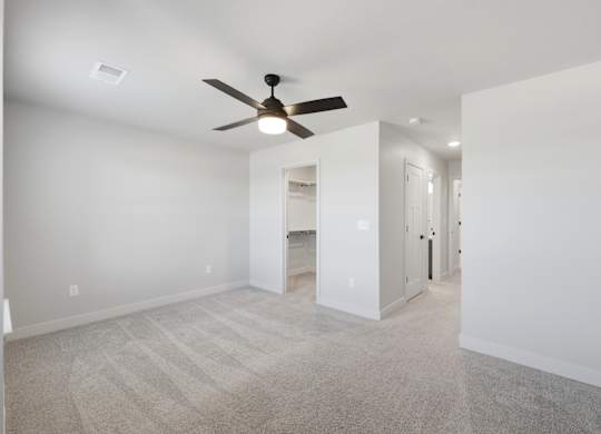 A room with a ceiling fan and carpeted floor.