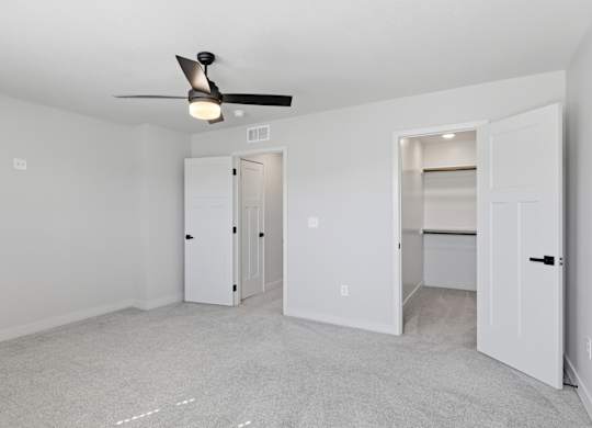 A room with a ceiling fan and two doors.