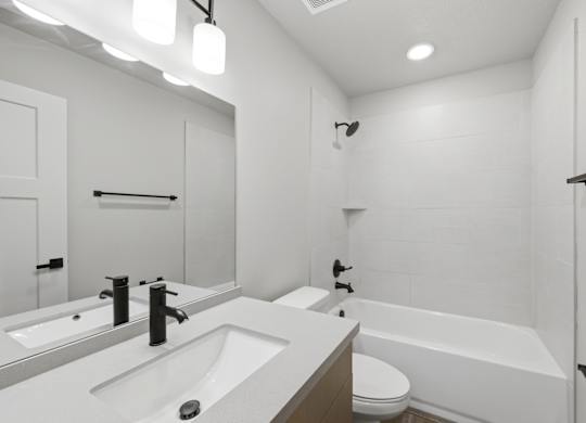 A white bathroom with a sink, toilet, and bathtub.
