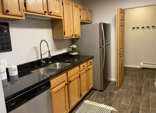 a kitchen with a sink and a refrigerator at Birchwood Apartment Homes in Maple Grove, MN