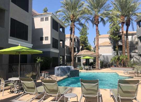 Dog-Friendly Garden-Style Apartments in Arcadia, AZ - The Ingleside Apartments - Swimming Pool with Hot Tub, Lounge Chairs, Shaded Seating, Gazebo, Palm Trees, and View of the Apartments.