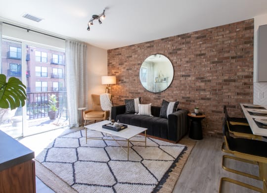 Maple Street Lofts - Spacious Living Room with Expansive Sliding Glass Door, Brick Accent Wall, and Furniture.