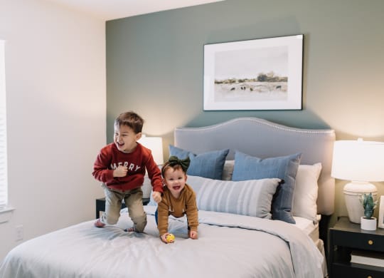 two young boys jumping on a bed