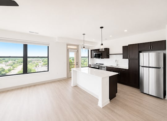 A modern kitchen with a large island and a view of the city.