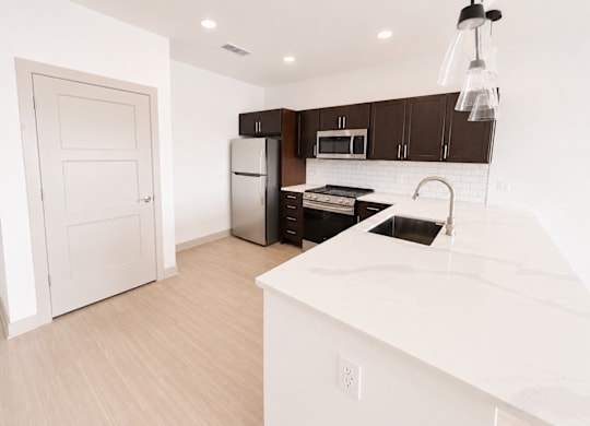 A kitchen with white countertops and dark brown cabinets.