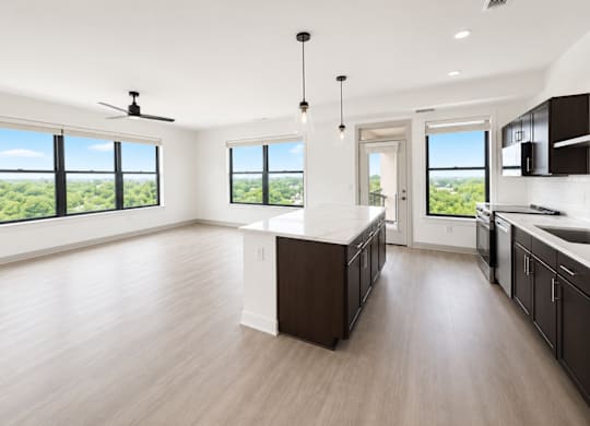 A spacious kitchen with a marble countertop and dark wood cabinets.
