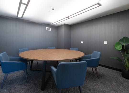 a small meeting room with a round table and blue chairs