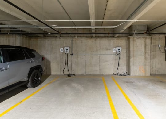 a car parked in a parking garage with two electric chargers plugged into the wall