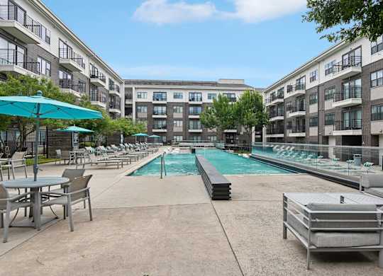 Markethaus 3700 Pool Views from Home A pool area with a table and chairs is surrounded by apartment buildings.
