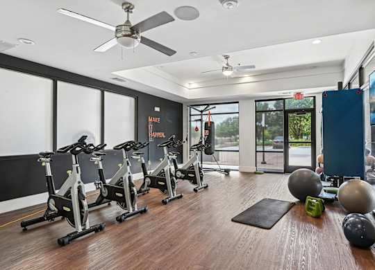 A gym with exercise equipment and a TV on the wall.