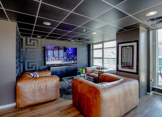 A living room with a brown leather sofa and a television.