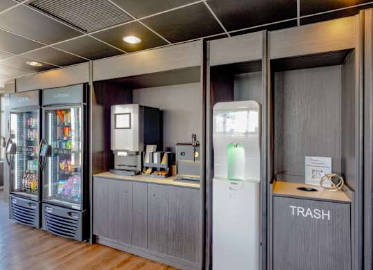 A room with a trash bin and a fridge.