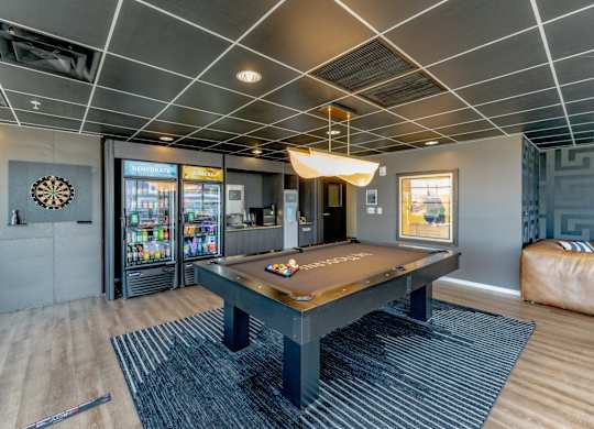 A room with a pool table and a dartboard on the wall.