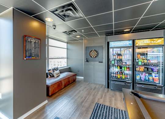 A room with a fridge and a dart board on the wall.