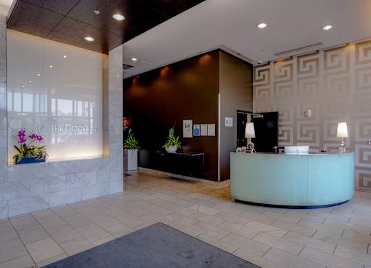 A reception area with a white counter and a black chair.
