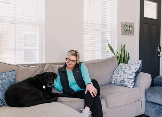 a woman sitting on a couch with a black dog