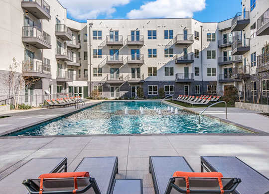 Sparkling resort style swimming pool with cushioned lounge chairs