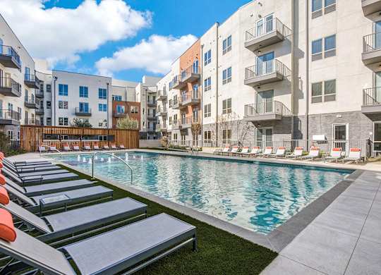 Sparkling resort style swimming pool with cushioned lounge chairs