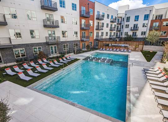 Sparkling resort style swimming pool with cushioned lounge chairs