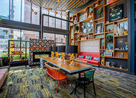 a dining room with a table and chairs in front of a wall filled with shelves