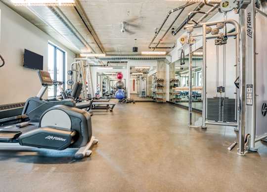 a gym with cardio equipment and weights on the floor