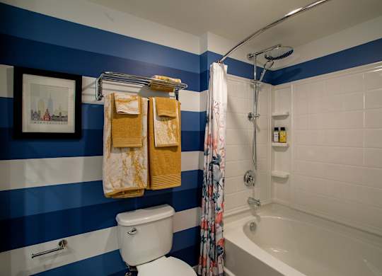 a bathroom with blue and white striped walls and a shower and a toilet and tub