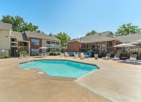 Mission, KS, Garden-Style Apartments Near Downtown Kansas City - Silverwood Apartments - A Swimming Pool Surrounded by Lounge Chairs and Apartment Buildings.