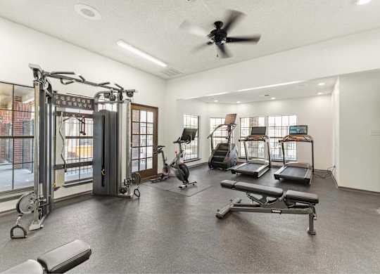 A spacious gym with a variety of equipment including treadmills, weights, and a rowing machine.