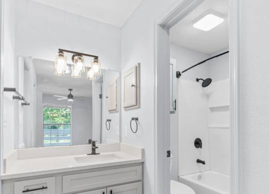 A white bathroom with a sink, mirror, and toilet.