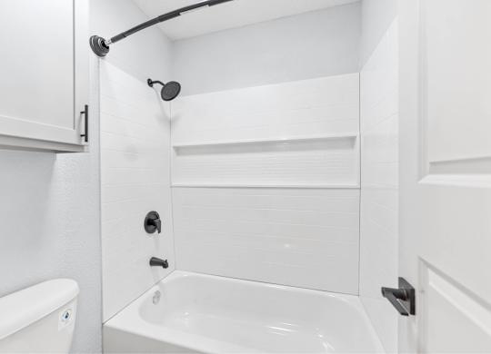 A white bathroom with a tub, shower, and toilet.