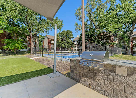 2-Bedroom Garden-Style Apartments in Mission, KS - Silverwood Apartments - An Outdoor Area Featuring a Fenced Sports Court Surrounded by Green Space.