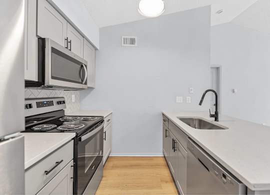 A modern kitchen with stainless steel appliances and a wooden floor.