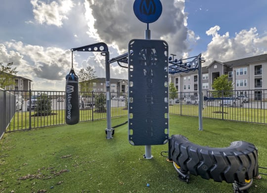 a playground with a tire swing and a sign in the grass