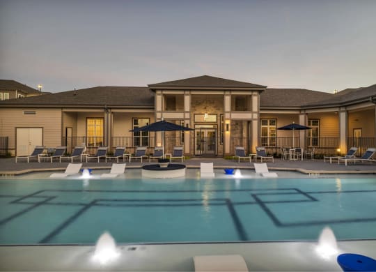 a large pool with chairs and umbrellas at dusk