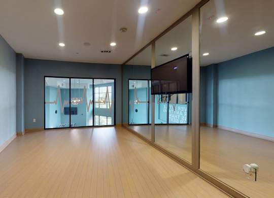 A spacious room with wooden floors and a television mounted on the wall.