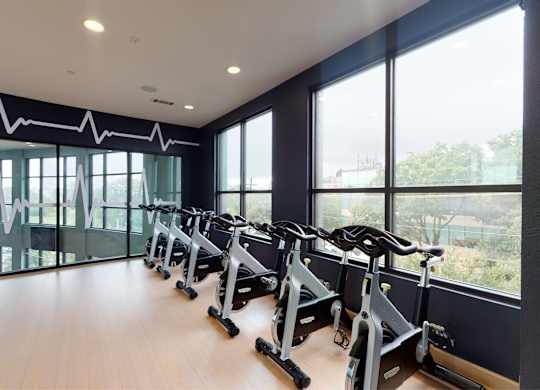 A gym with a row of stationary bikes and a heartbeat line on the wall.