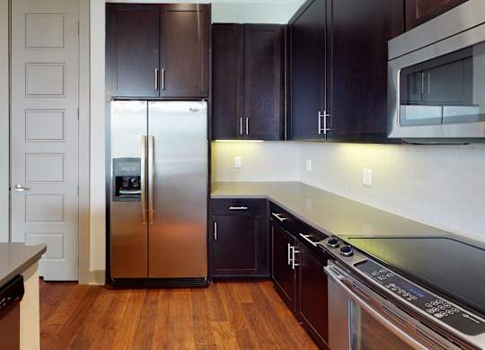 A kitchen with a refrigerator, oven, and microwave.
