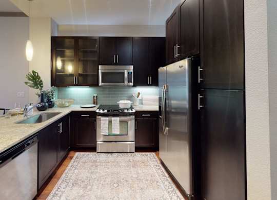 A modern kitchen with a refrigerator, microwave, and oven.