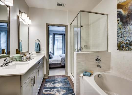 Spa inspired bathroom with shower and tub combo and dual sink vanity at at Midway Urban Village Luxury Townhomes and loft apartments in Farmers Branch, Texas near North Dallas. Luxury North Dallas Tow